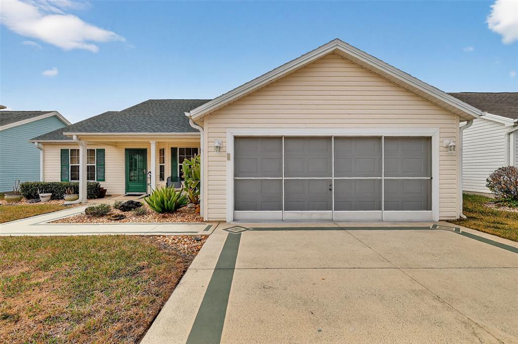 A single-story house with beige siding, a green front door, and a garage screen door — 648 SAN MARINO DRIVE, THE VILLAGES, FL