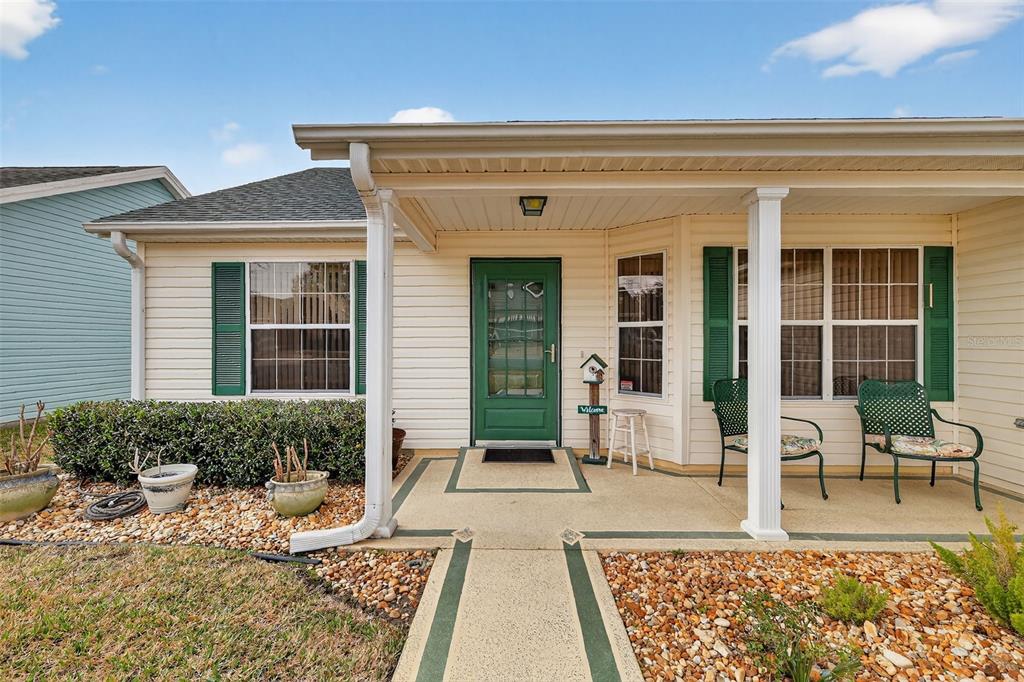 A single-story house exterior features a covered front porch, green door, and green shutters — 648 SAN MARINO DRIVE, THE VILLAGES, FL