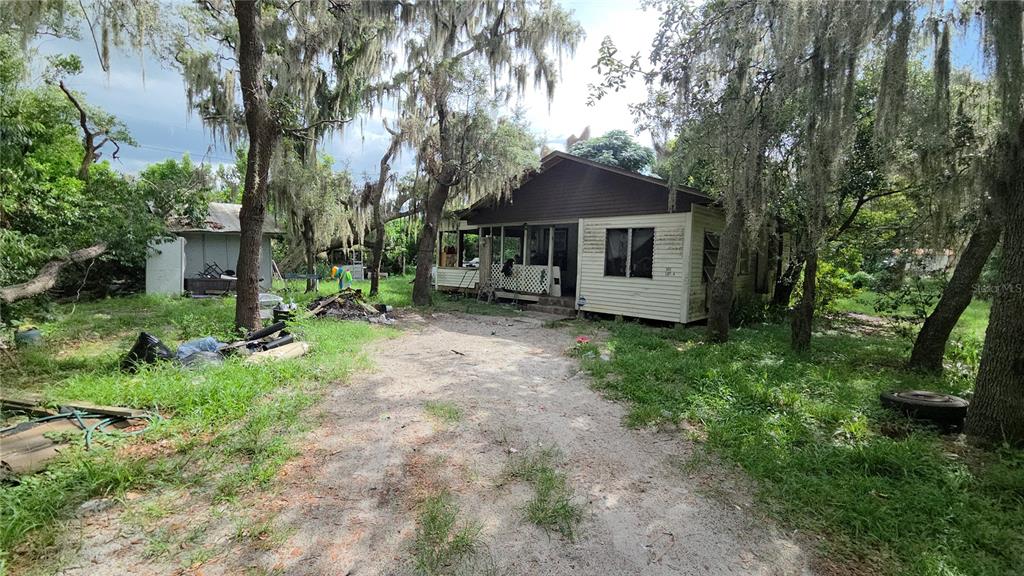 A weathered house with a front porch sits on a dirt lot surrounded by trees — 365 80 FOOT ROAD UNIT 4, BARTOW, FL
