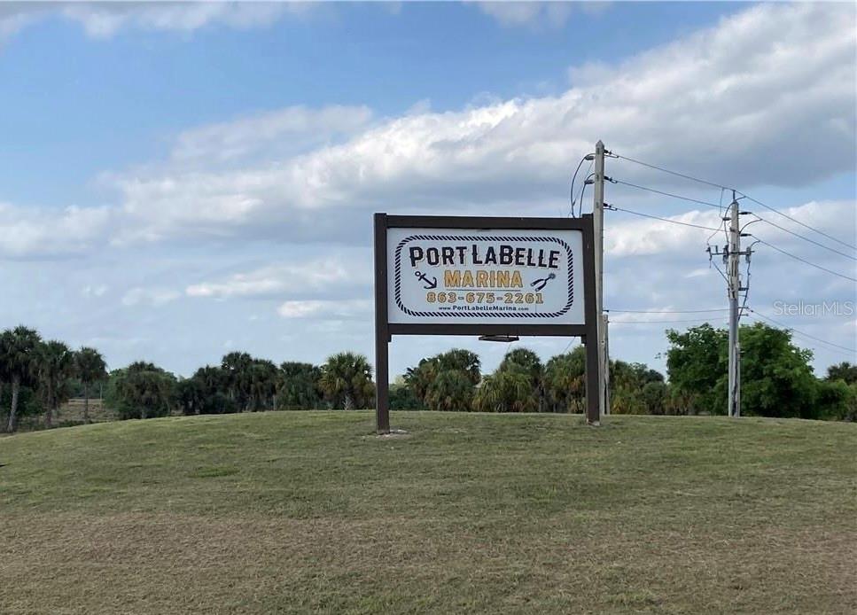 A sign for Port LaBelle Marina stands on a grassy hill under a cloudy sky — 208 ELMWOOD STREET, LABELLE, FL