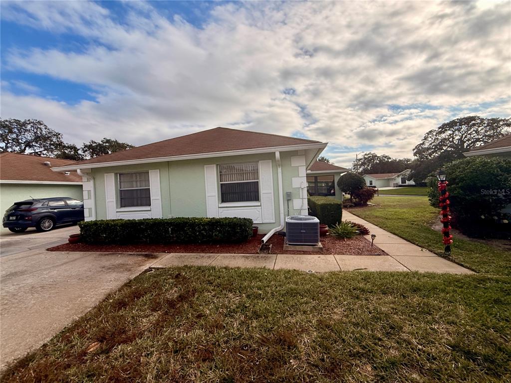 A light green single-story house exterior features a brown roof, white shutters, and landscaping — 8350 HIGH POINT CIRCLE UNIT 3, PORT RICHEY, FL