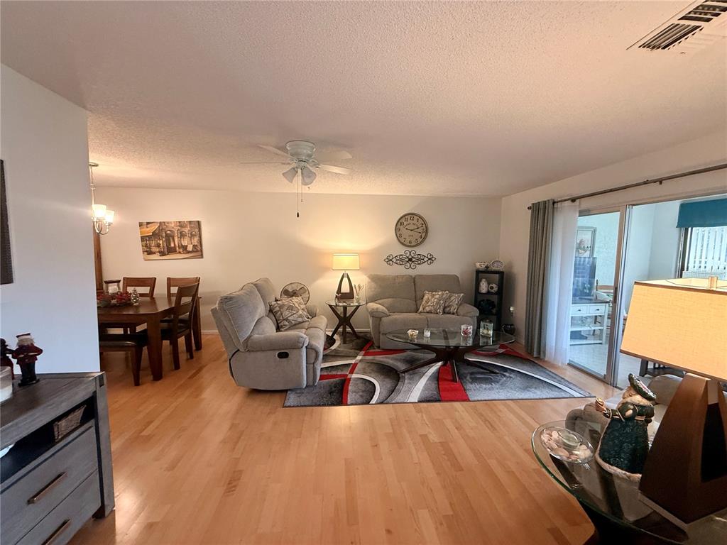 A living room with hardwood floors, a gray sofa set, and a dining area — 8350 HIGH POINT CIRCLE UNIT 3, PORT RICHEY, FL