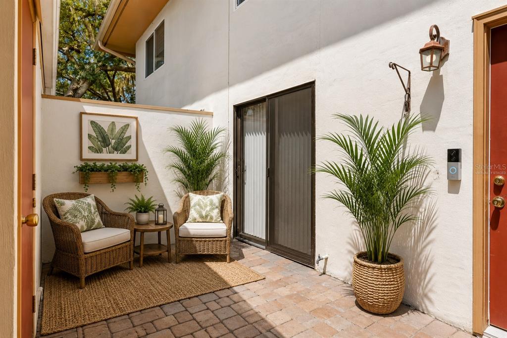 A paved outdoor patio features two wicker chairs, a small table, and potted plants — 408 HOWARD AVENUE UNIT B, LAKELAND, FL