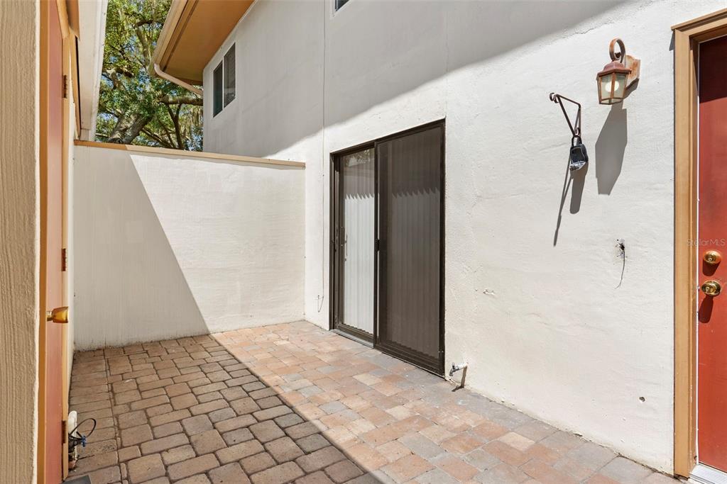 A paved patio area sits between a white wall and a red door — 408 HOWARD AVENUE UNIT B, LAKELAND, FL