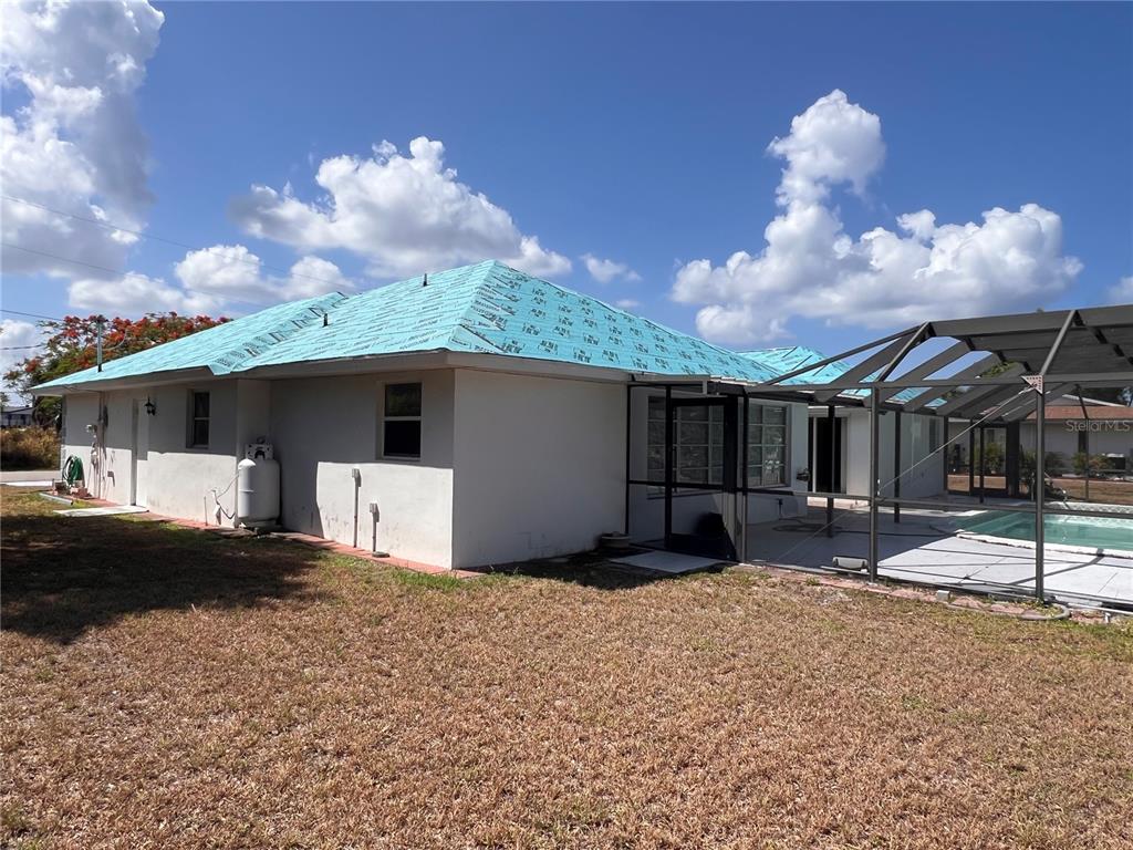 The exterior of a house with a blue underlayment roof and an attached pool enclosure — 4419 CREWS COURT, PORT CHARLOTTE, FL