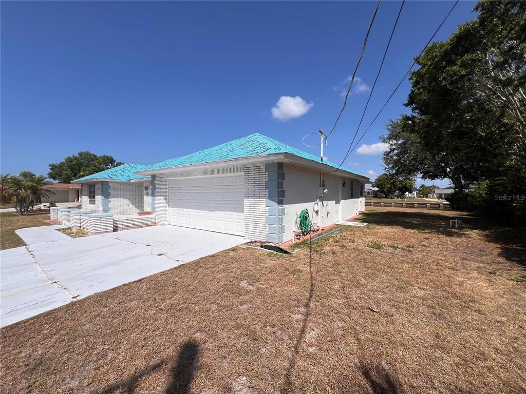 A single-story house with a white garage door and a blue underlayment roof — 4419 CREWS COURT, PORT CHARLOTTE, FL