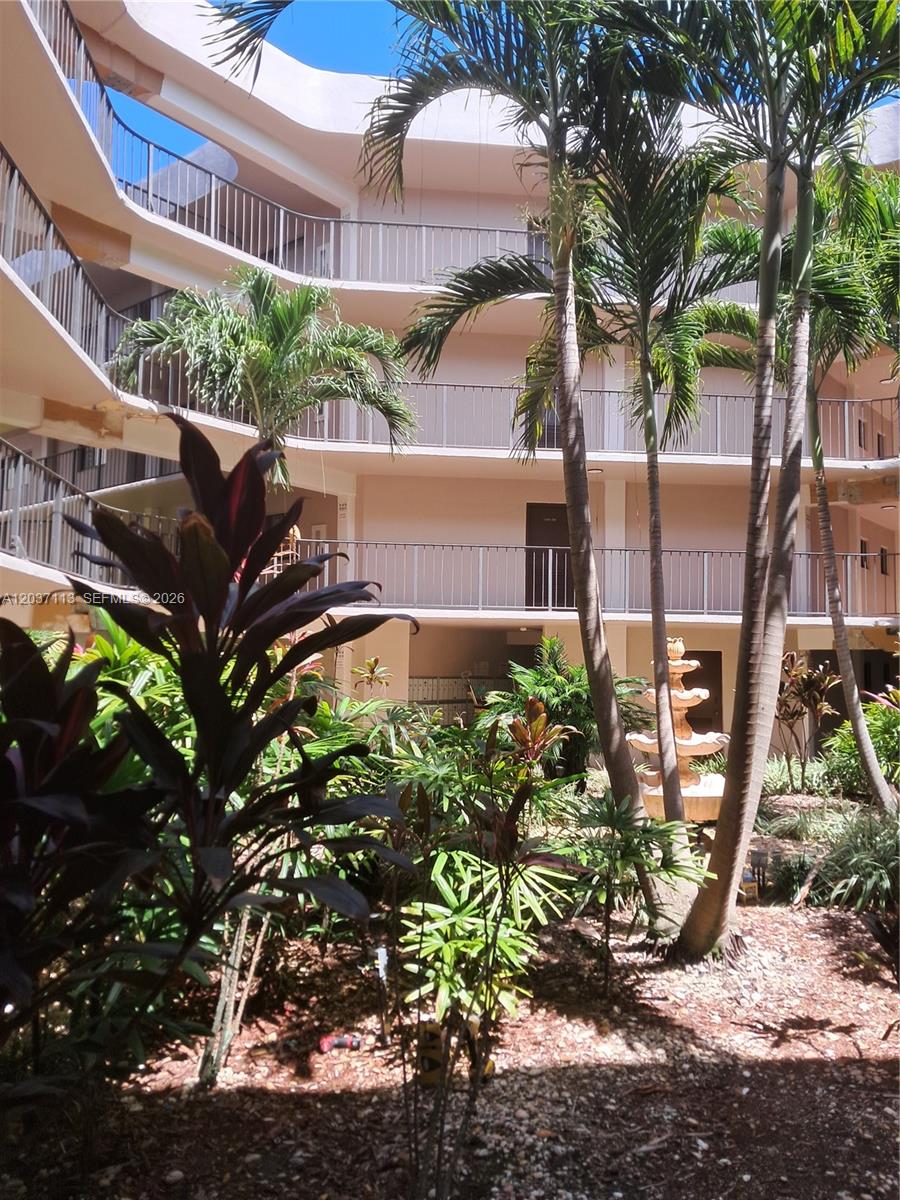 A multi-story apartment building courtyard features a central fountain surrounded by palm trees and plants — 8420 SW 133rd Ave Rd # 120, Miami FL 33183, MIAMI, FL