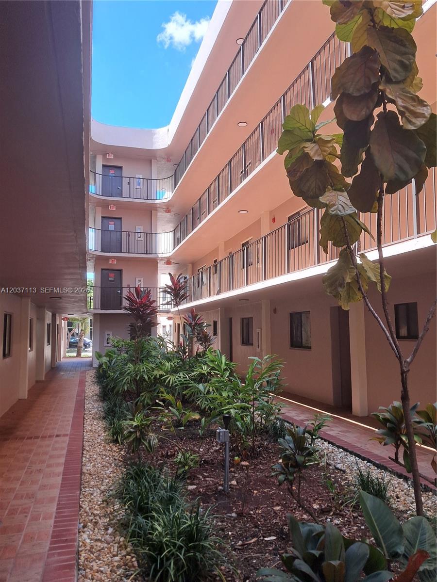 An exterior view of a multi-story apartment building with an open-air courtyard and landscaping — 8420 SW 133rd Ave Rd # 120, Miami FL 33183, MIAMI, FL