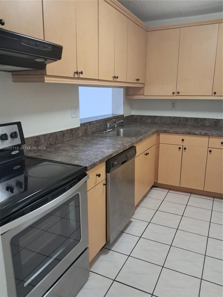 A kitchen features light wood cabinets, dark laminate countertops, and stainless steel appliances — 8420 SW 133rd Ave Rd # 120, Miami FL 33183, MIAMI, FL