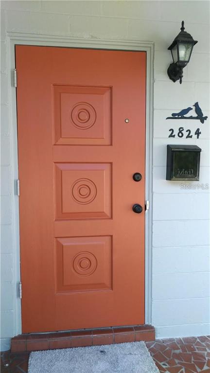 A bright orange front door with three square panels sits next to a wall-mounted mailbox — 2824 WOODSIDE AVENUE, WINTER PARK, FL