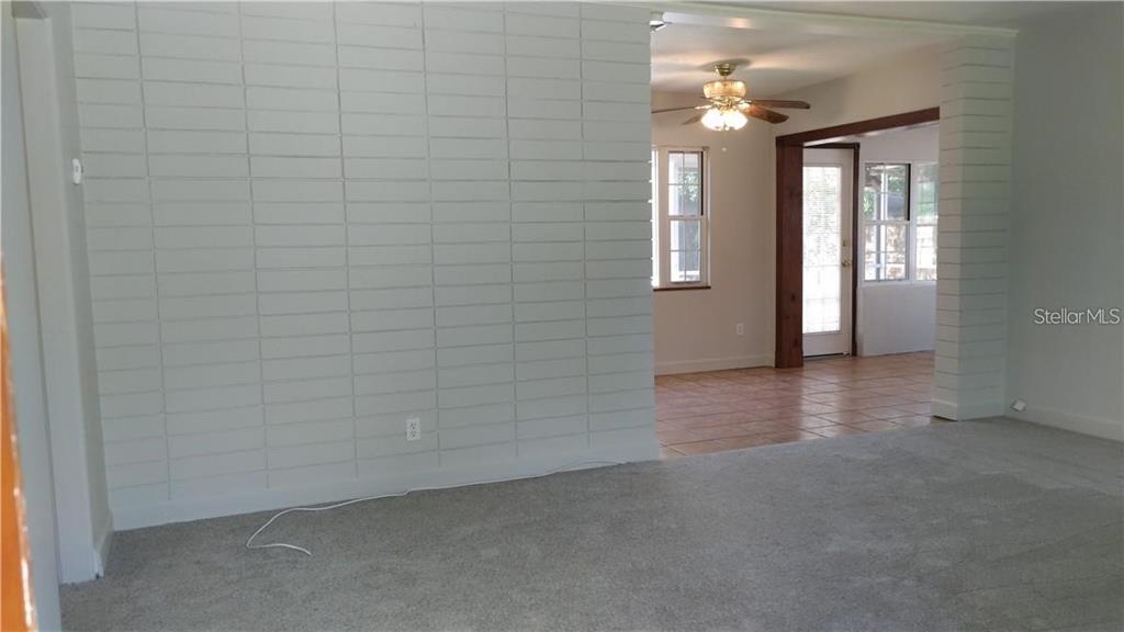 A living room with gray carpet and a white painted brick accent wall — 2824 WOODSIDE AVENUE, WINTER PARK, FL