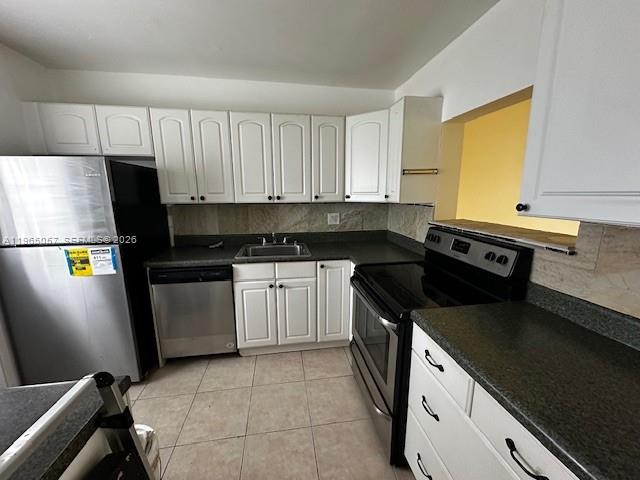 A kitchen features white cabinets, dark countertops, stainless steel appliances, and light-colored tile flooring — 2223 Park Ln # 304, Hollywood FL 33021, HOLLYWOOD, FL