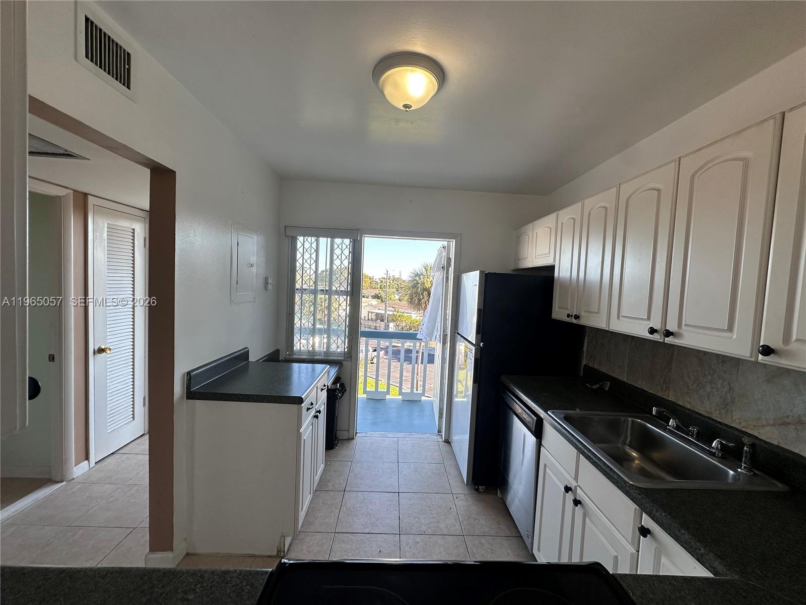 A kitchen pass-through window overlooks a living area with a ceiling fan and large windows — 2223 Park Ln # 304, Hollywood FL 33021, HOLLYWOOD, FL