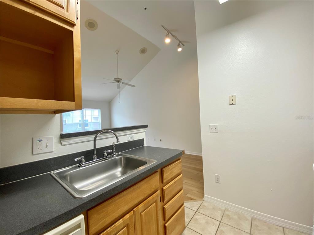 A kitchen sink with a stainless steel basin sits in a dark countertop with cabinets — 3364 WESTCHESTER SQUARE BOULEVARD UNIT 205, ORLANDO, FL