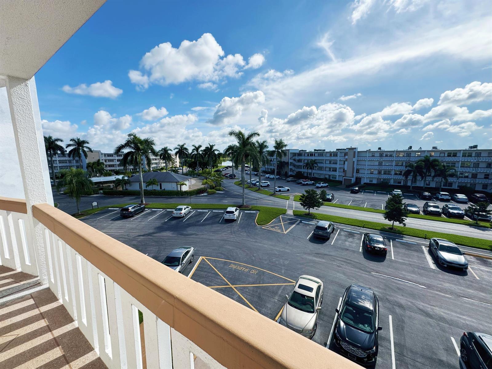 A high-angle view from a balcony overlooking a parking lot and apartment buildings — 4075 Cornwall D, Boca Raton FL 33434, BOCA RATON, FL