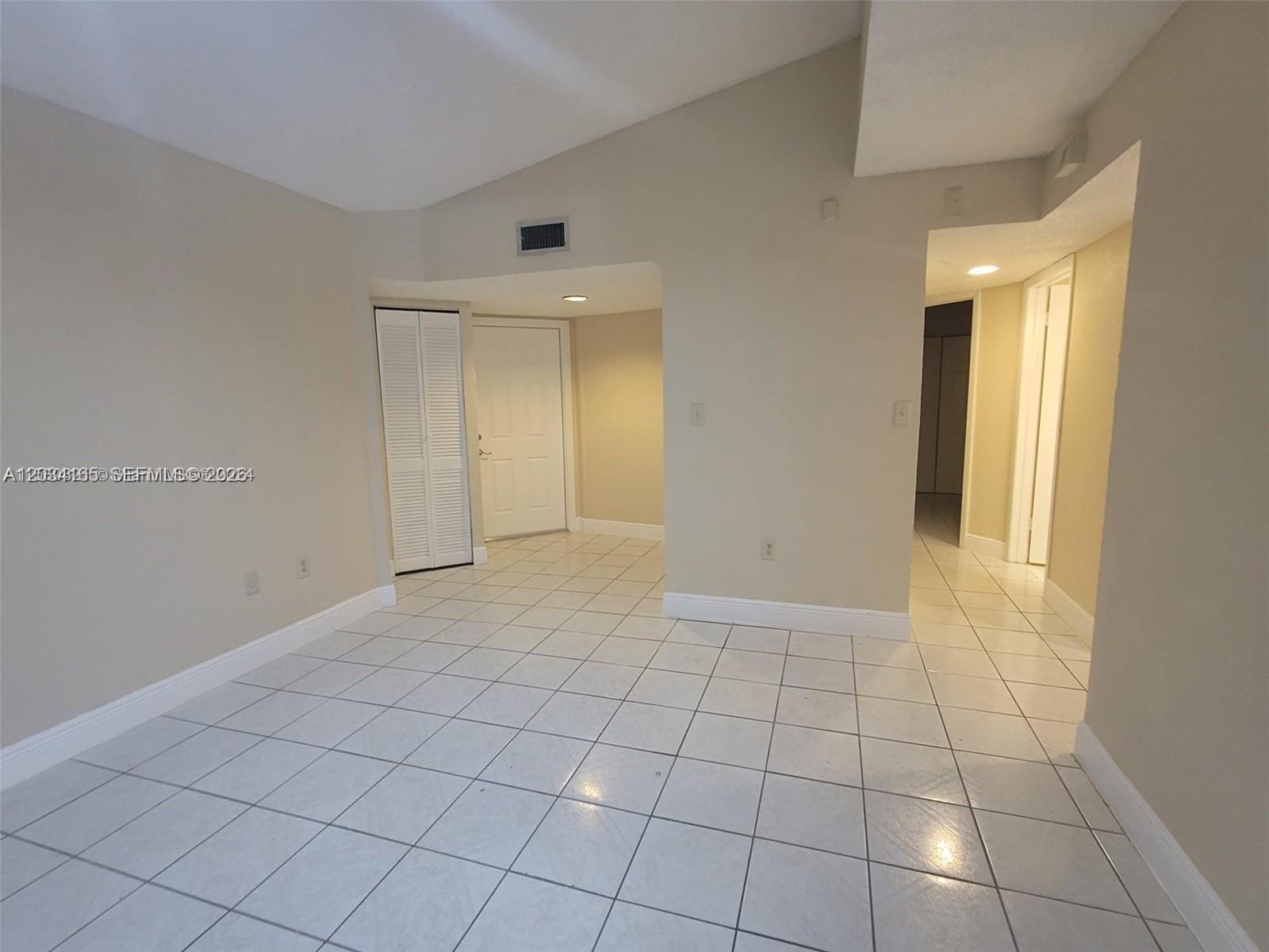 A room with light-colored tile flooring, beige walls, a vaulted ceiling, and a closet — 9673 SW 138th Ave, Miami FL 33186, MIAMI, FL