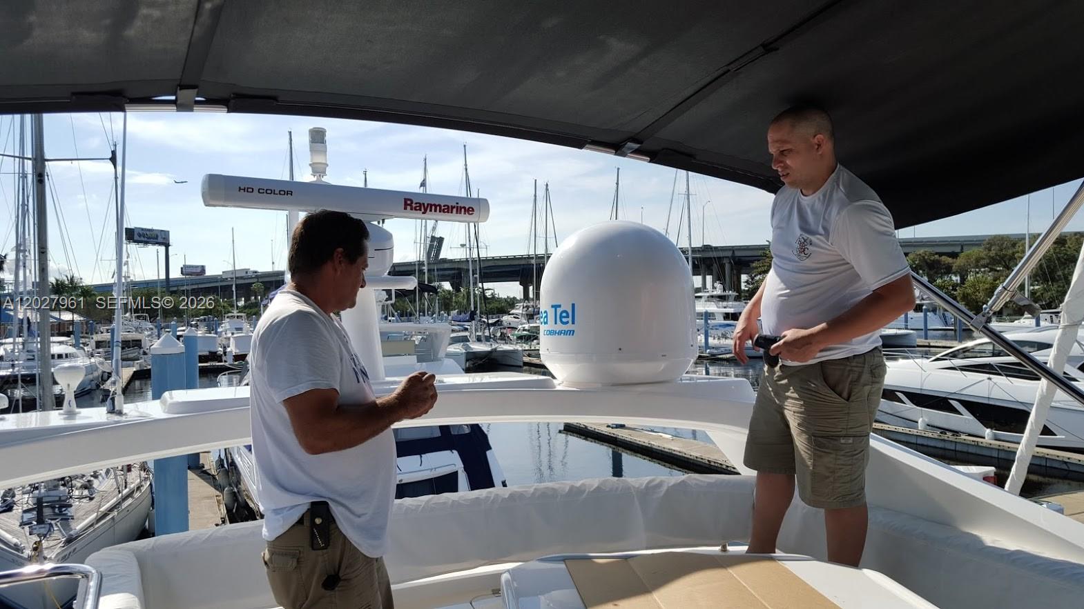 Two men stand on the deck of a boat near a radar and satellite dome — MIAMI, FL