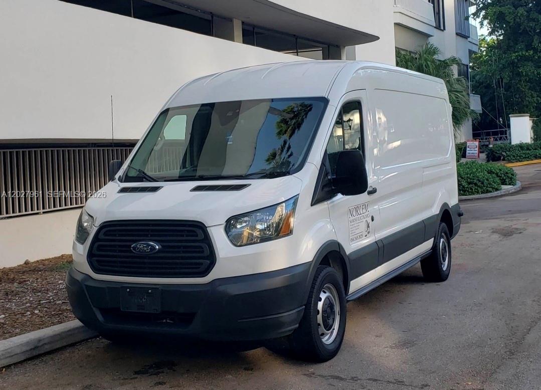 A white Ford Transit cargo van is parked on an asphalt surface near a building — MIAMI, FL