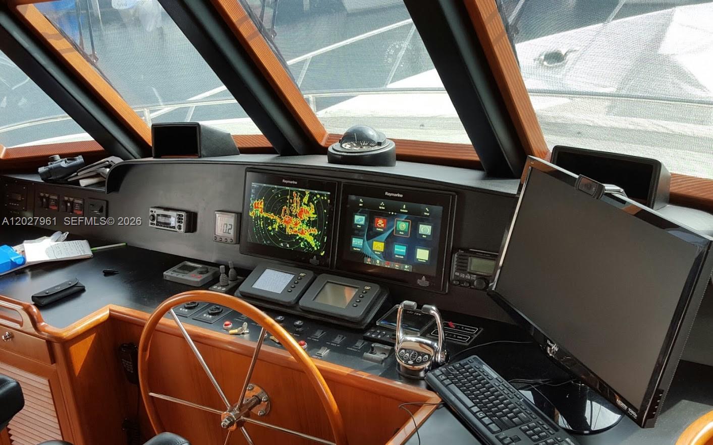 The boat cockpit features a wooden steering wheel, multiple navigation screens, and a computer monitor — MIAMI, FL