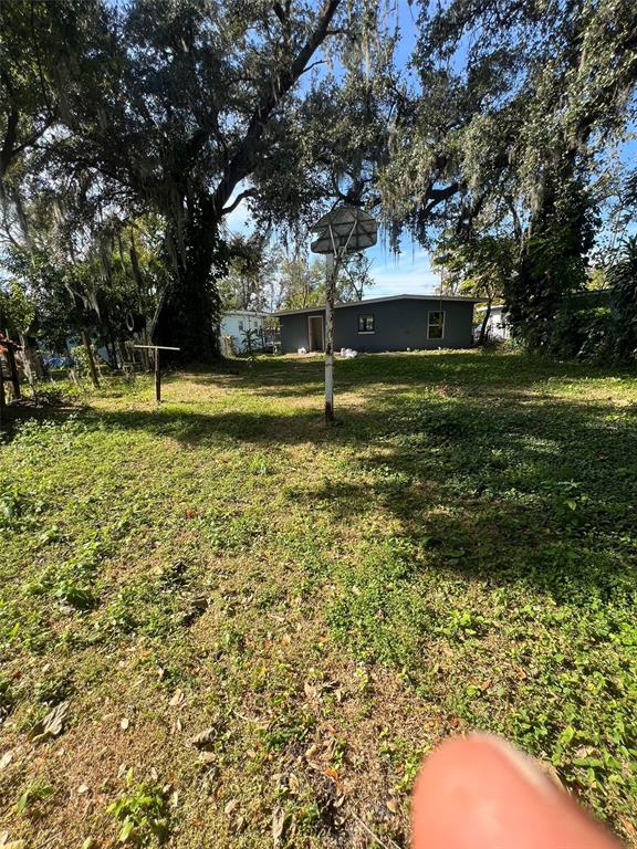 A backyard features a basketball hoop, large trees with Spanish moss, and a small house — 1505 S WESTMORELAND DRIVE, ORLANDO, FL