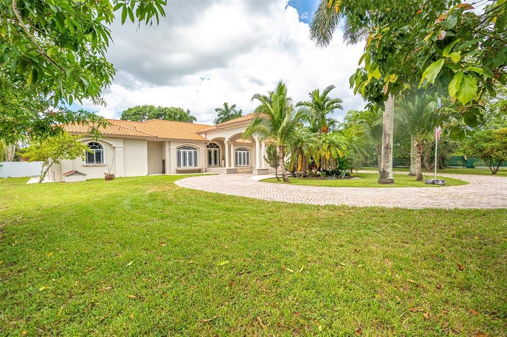A single-story house with a tiled roof, arched windows, and a circular paved driveway — 18390 SW 200TH STREET, MIAMI, FL