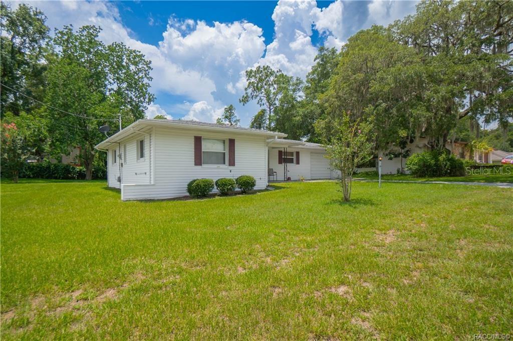 A white, single-story house with a garage and brown shutters sits on a grassy lot — 519 POPLAR STREET, INVERNESS, FL