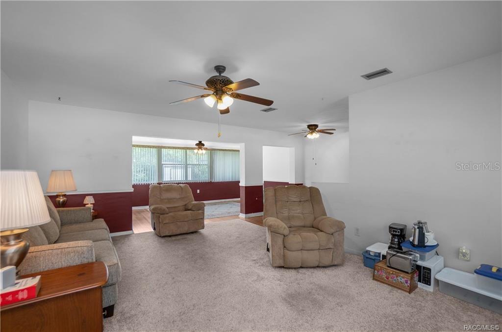 A living room features beige carpet, two recliners, a sofa, and a ceiling fan — 519 POPLAR STREET, INVERNESS, FL