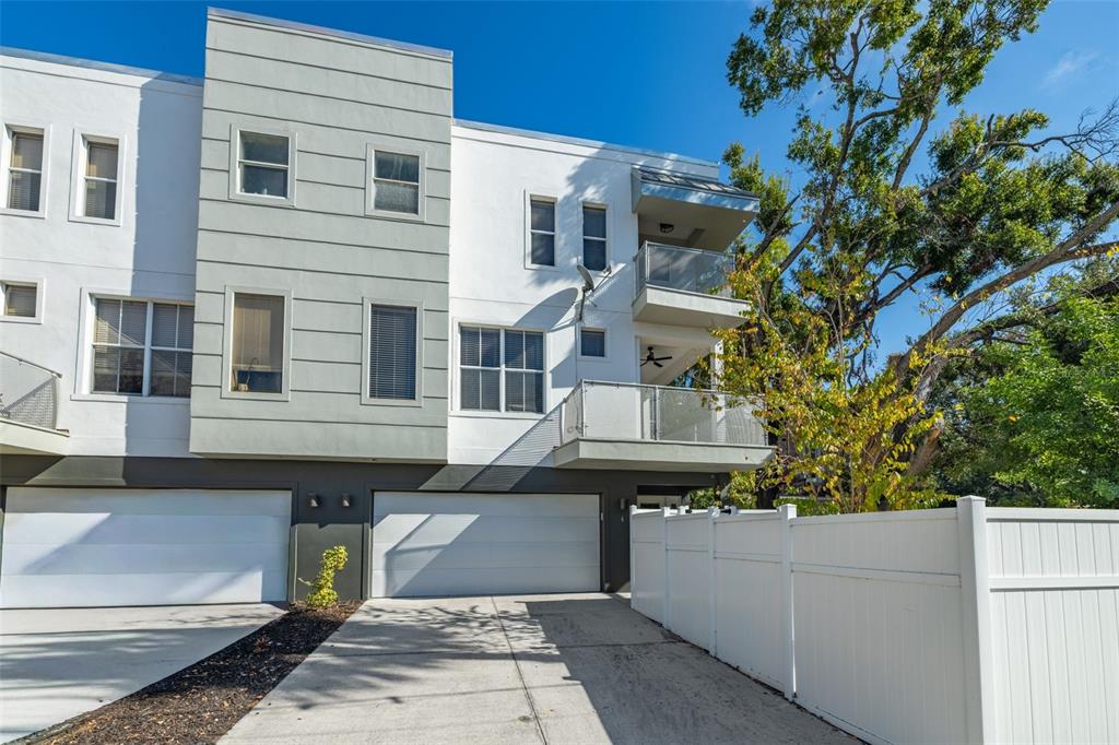A modern three-story townhouse exterior features white and gray siding, balconies, and two garage doors — 113 S NEWPORT AVENUE UNIT 1-4, TAMPA, FL