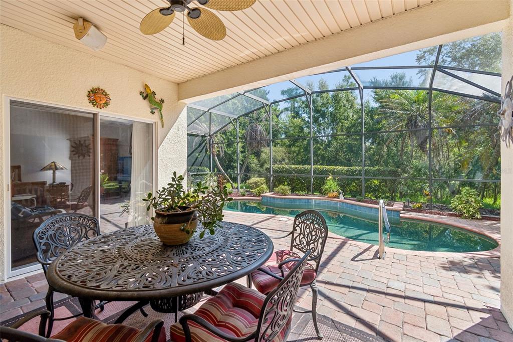 A covered patio features a metal dining set, a ceiling fan, and a screened-in pool — 729 CORONADO DRIVE, POINCIANA, FL