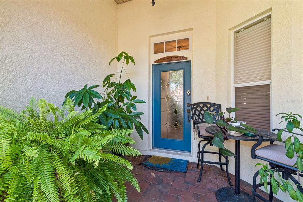 A blue front door with a glass insert sits on a brick porch with plants — 729 CORONADO DRIVE, POINCIANA, FL