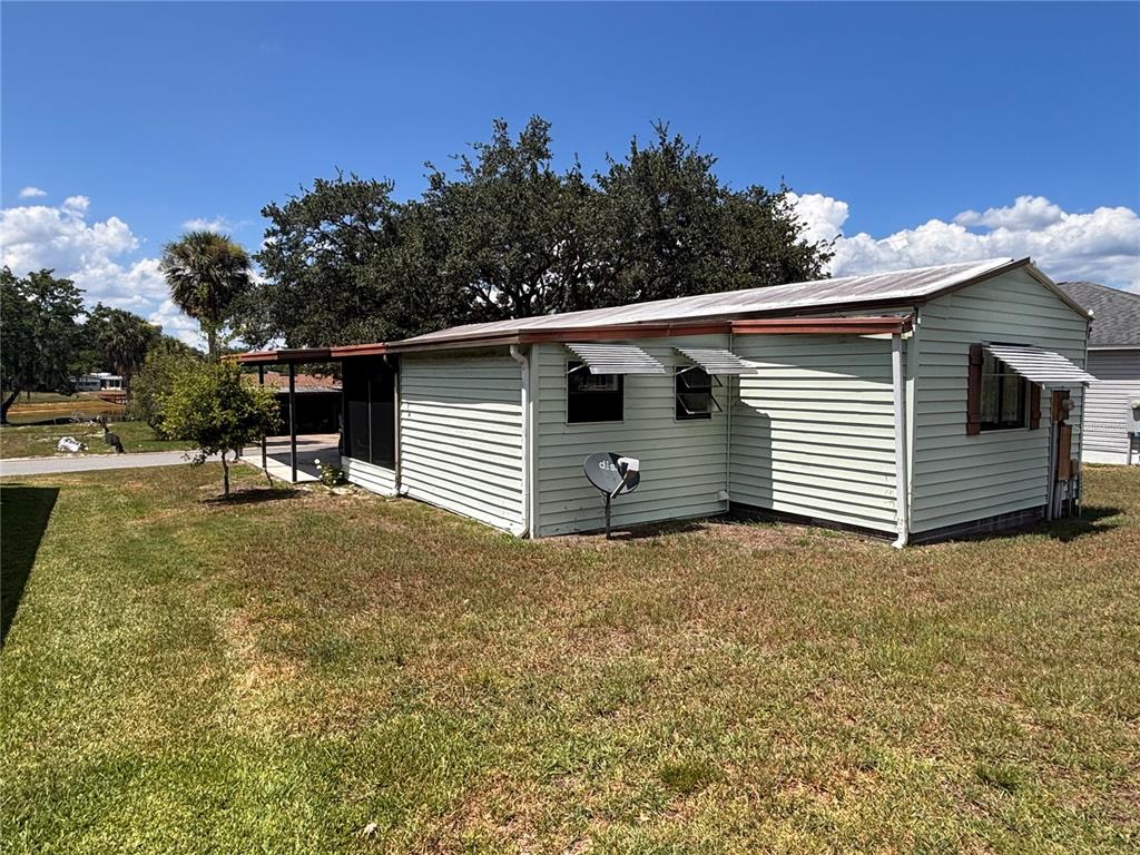 A light green mobile home with a metal roof and a screened-in porch area — 945 TARRSON BOULEVARD, LADY LAKE, FL