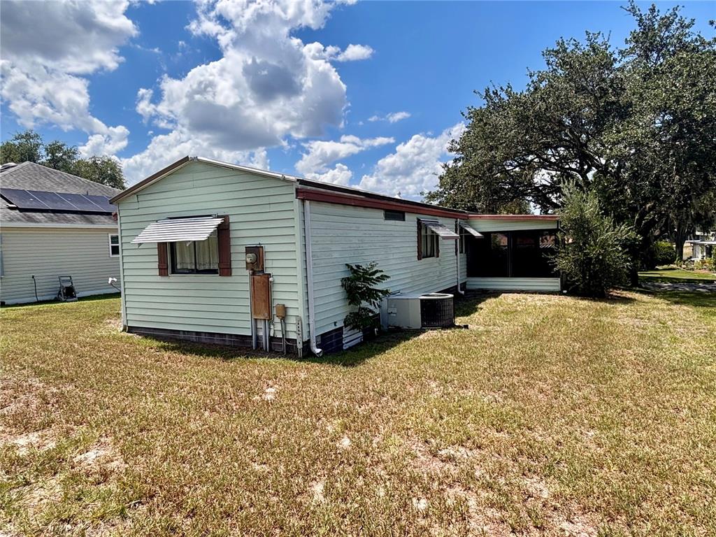 A light green mobile home with a metal awning and an attached screened porch — 945 TARRSON BOULEVARD, LADY LAKE, FL