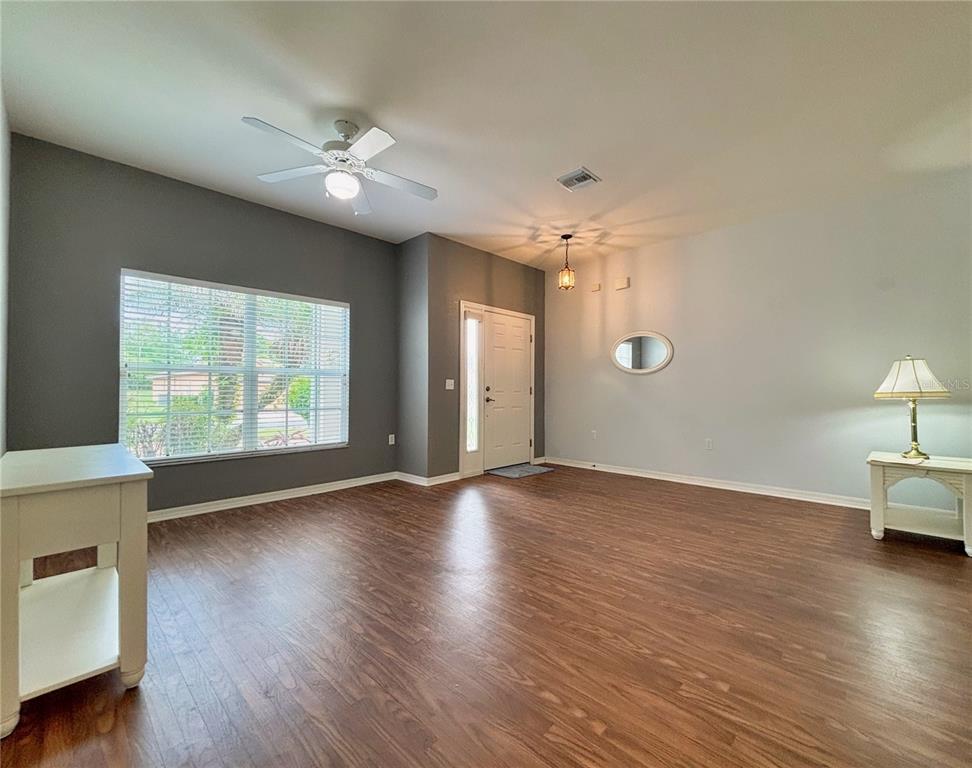 A living room with wood-look flooring, a ceiling fan, and a front entryway door — 4493 TURNBERRY LANE, LAKE WALES, FL
