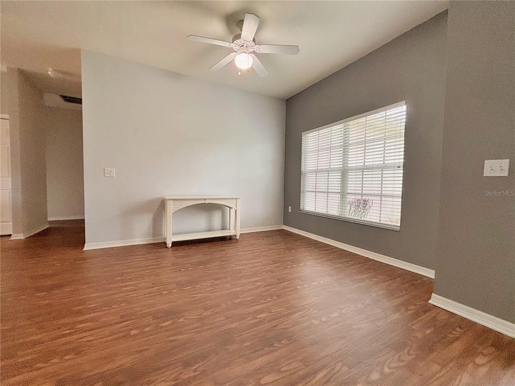 A room with wood-look flooring, a ceiling fan, and a white console table — 4493 TURNBERRY LANE, LAKE WALES, FL