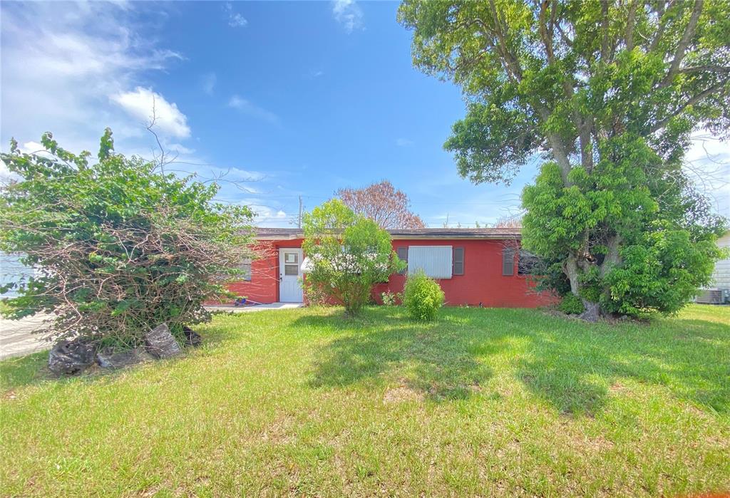 A single-story red brick house sits behind a grassy lawn with several large trees — 4425 BROWNING AVENUE, TITUSVILLE, FL