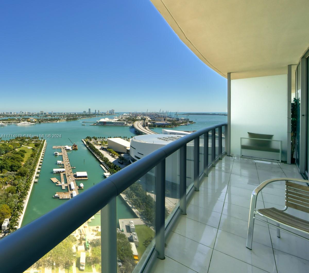 A high-rise balcony with a glass railing overlooks a marina, a bridge, and the ocean — 888 Biscayne Blvd # 2511, Miami FL 33132, MIAMI, FL