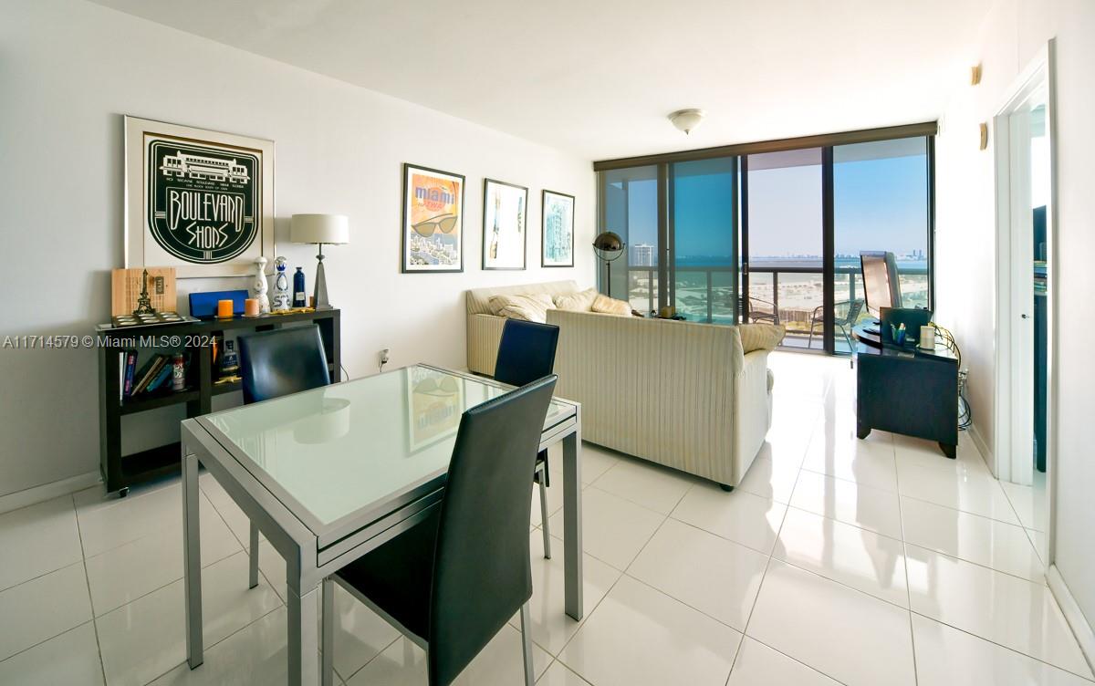 A living and dining area features white tile floors, a glass-top table, and balcony views — 888 Biscayne Blvd # 2511, Miami FL 33132, MIAMI, FL