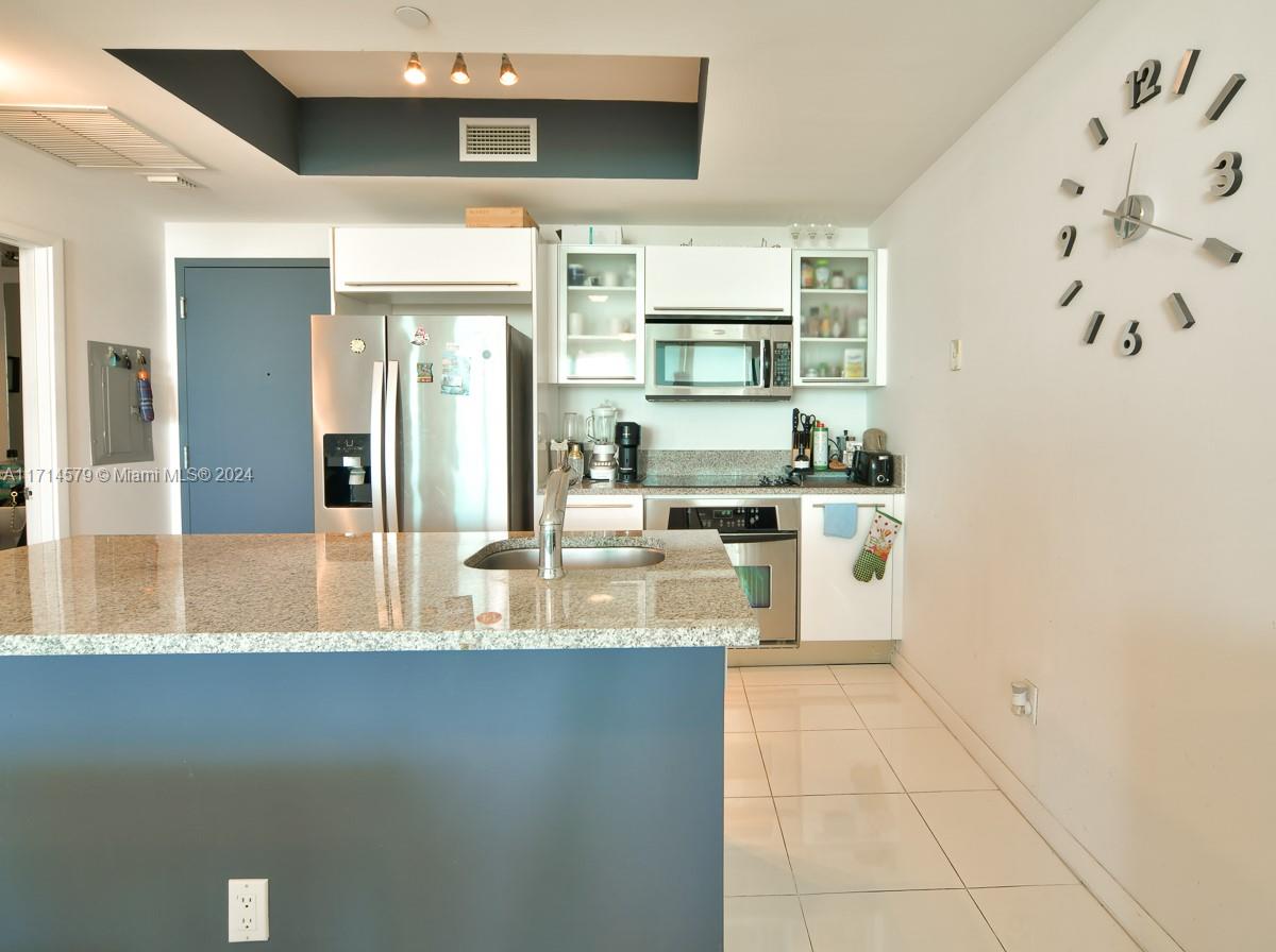 A kitchen features white cabinets, stainless steel appliances, granite countertops, and a blue island — 888 Biscayne Blvd # 2511, Miami FL 33132, MIAMI, FL