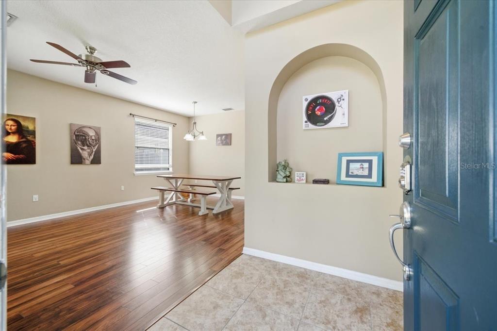 An entryway with tile flooring leads into a dining room featuring wood floors and an archway — 11844 COLONY LAKES BOULEVARD, NEW PORT RICHEY, FL