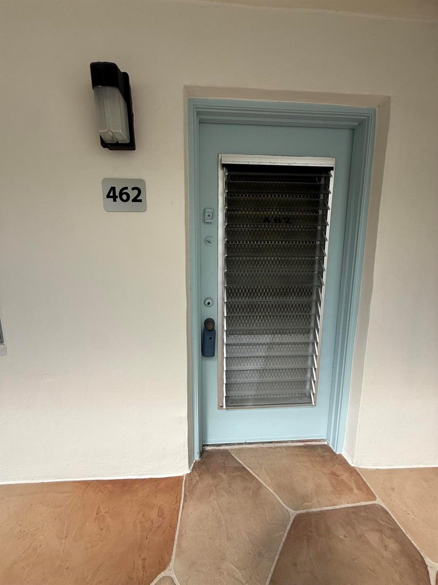 A light blue door with jalousie windows and the number 462 sits in a white wall — 462 Normandy J, Delray Beach FL 33484, DELRAY BEACH, FL