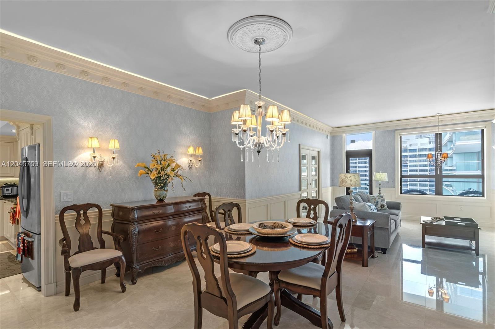 A dining area with a chandelier and wooden furniture opens into a living room space — 10185 Collins Ave, Bal Harbour FL 33154, BAL HARBOUR, FL