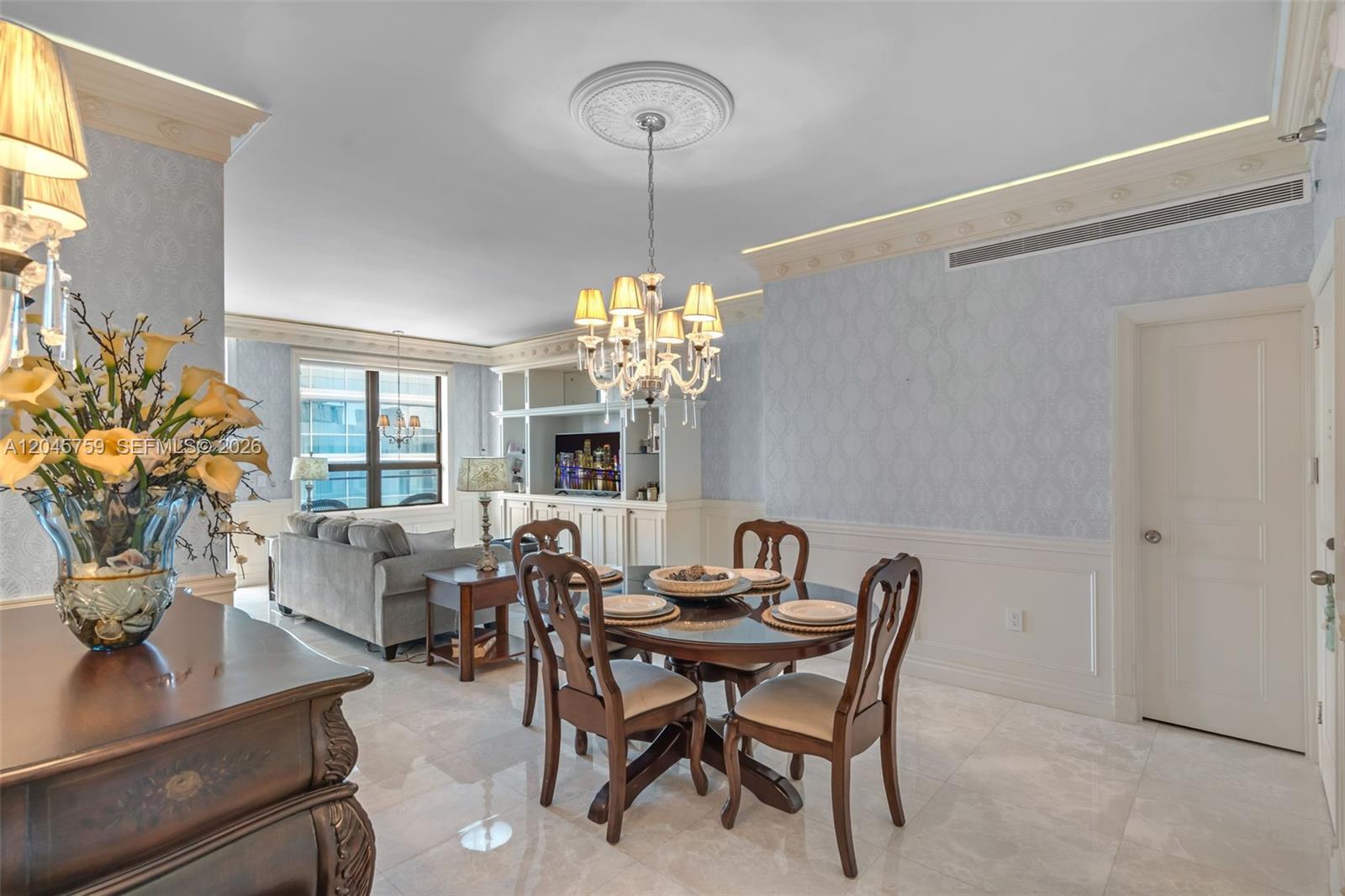 A dining area features a round table, wooden chairs, a chandelier, and light blue wallpaper — 10185 Collins Ave, Bal Harbour FL 33154, BAL HARBOUR, FL