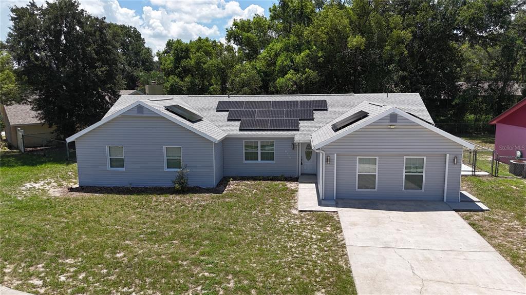 A single-story house with gray siding, a concrete driveway, and solar panels on the roof — 6120 CENTENNIAL DRIVE, ORLANDO, FL