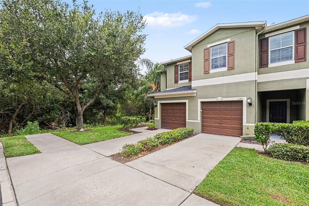A two-story townhouse with two brown garage doors, green stucco siding, and a concrete driveway — 2711 ISABELLA VALLEY COURT, BRANDON, FL