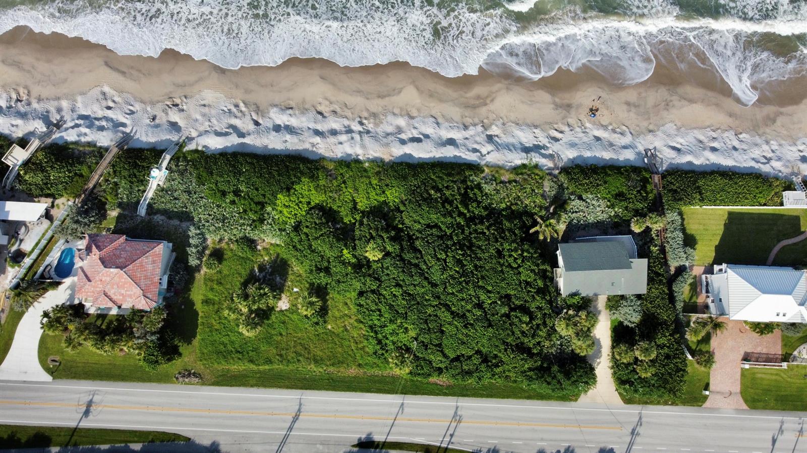 An aerial view shows a vacant lot situated between two houses along a sandy beach — 7703 S Hwy A1a, Melbourne Beach FL 32951, MELBOURNE BEACH, FL