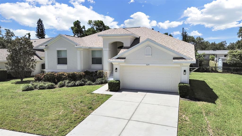 A single-story house with a white stucco exterior, a two-car garage, and a concrete driveway — 1025 LAKE AVOCA PLACE, TARPON SPRINGS, FL