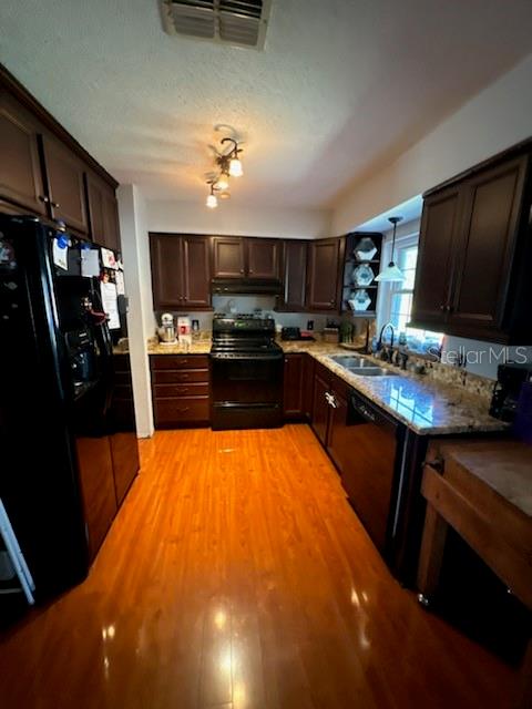 A kitchen features dark wood cabinets, granite countertops, stainless steel appliances, and hardwood flooring — 4325 CAROLYN WAY, BARTOW, FL