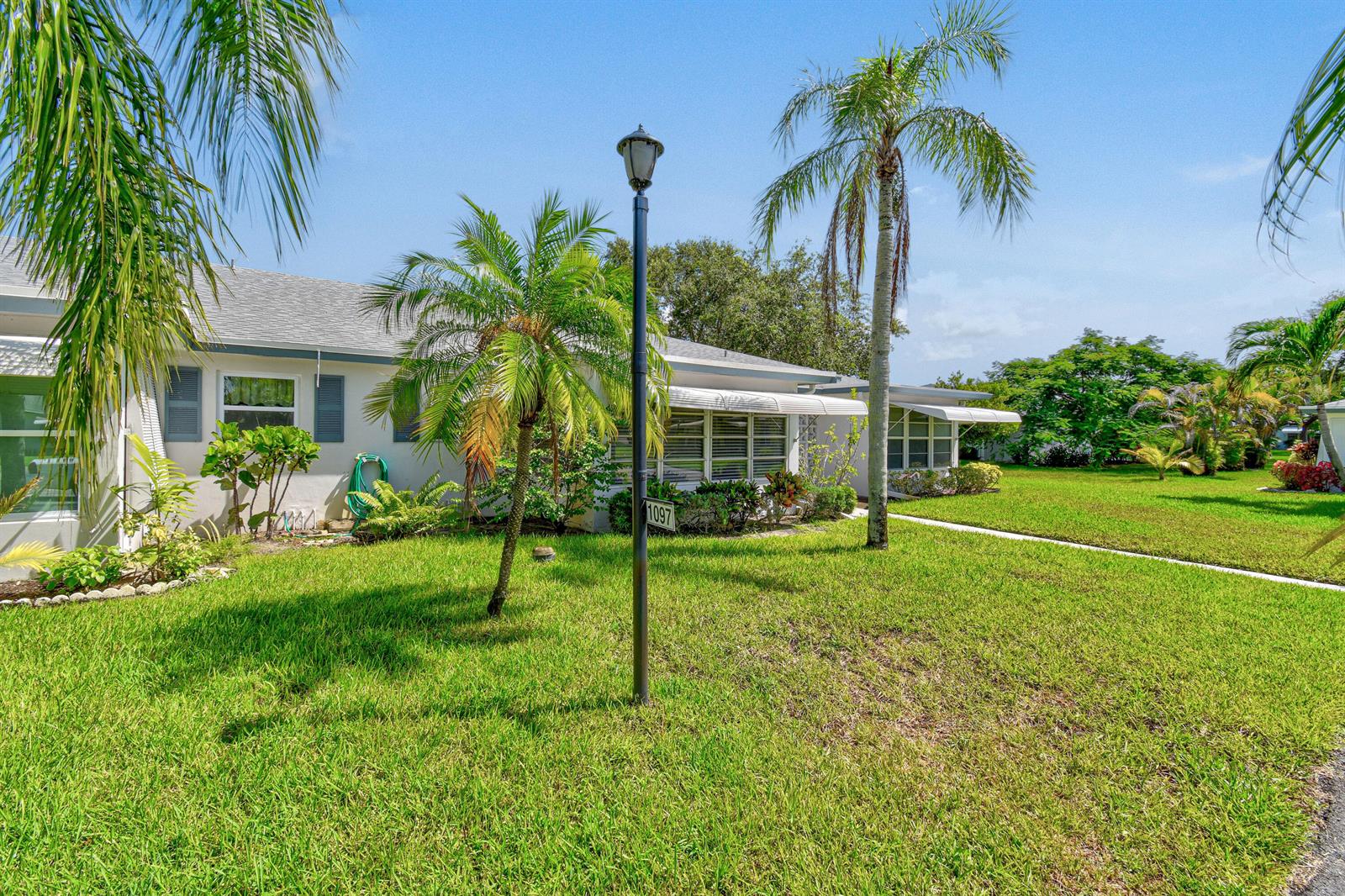 A single-story house with a lawn, palm trees, and a lamp post in the front yard — 1097 Circle Terrace W # C, Delray Beach FL 33445, DELRAY BEACH, FL