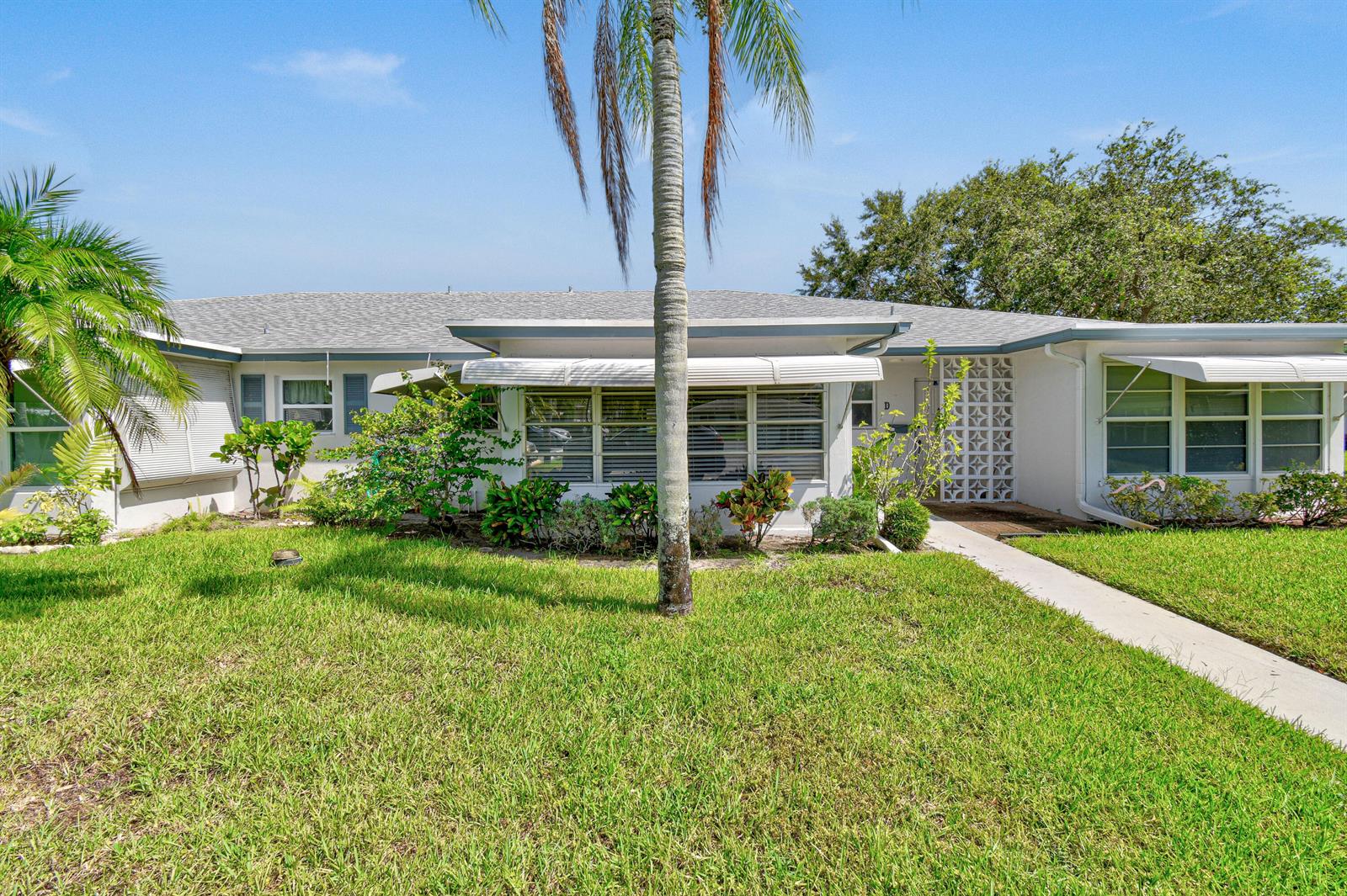 A single-story residential building features a white facade, a palm tree, and a grassy lawn — 1097 Circle Terrace W # C, Delray Beach FL 33445, DELRAY BEACH, FL