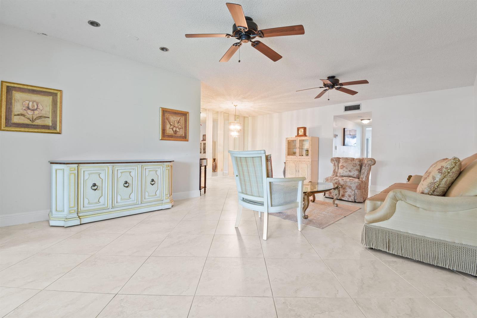 A bright living room features tile flooring, two ceiling fans, and traditional furniture — 1097 Circle Terrace W # C, Delray Beach FL 33445, DELRAY BEACH, FL
